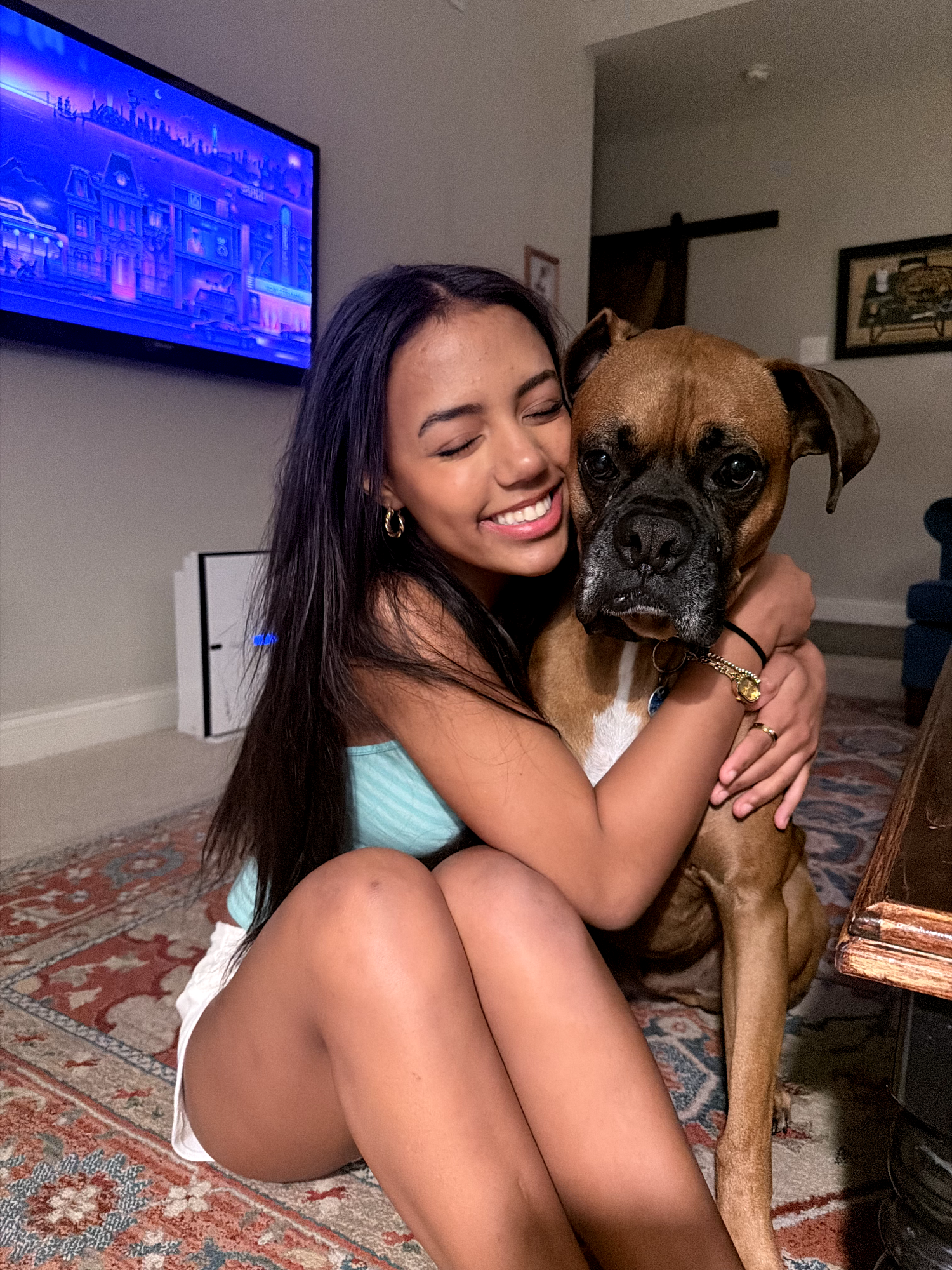 J smiling and hugging a boxer dog